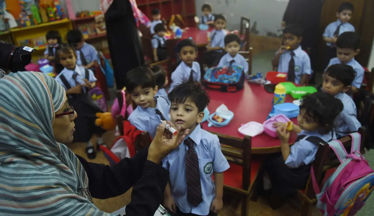 Pekerja kesehatan Pakistan memberi vaksin polio ke seorang anak di Karachi (9/4). Pakistan adalah salah satu dari hanya dua negara di dunia di mana polio, penyakit masa kecil yang melumpuhkan. (AFP Photo/Rizwan Tabassum)