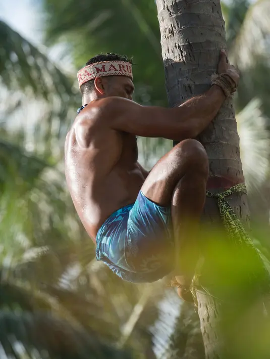 Peserta berusaha memanjat pohon kelapa saat mengikuti kejuaraan dunia pertama panjat pohon kelapa di Papeete, Polinesia (15/7). Kompetisi ini juga sebagai bagian dari festival budaya besar bagi orang Polinesia. (AFP Photo/Gregory Boissy)
