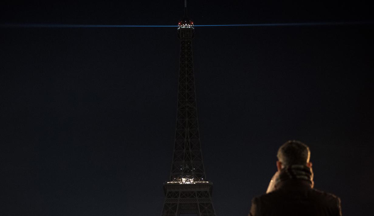 Seorang pria mengambil gambar lampu Menara Eiffel yang dipadamkan sementara di Paris, Rabu (14/12). Lampu Menara Eiffel dimatikan untuk menunjukkan dukungan bagi warga Aleppo di Suriah. (AFP PHOTO/PHILIPPE LOPEZ)