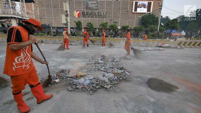 Petugas Penanganan Prasarana dan Sarana Umum (PPSU) atau Pasukan Oranye membersihkan sisa puing-puing pasca kerusuhan di MH. Thamrin. (Liputan6.com/Herman Zakharia)