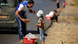 Seorang pria membeli roti tradisional yang dijajakan seorang bocah di pinggiran Algiers, Aljazair, 13 Juni 2016. Selama bulan Ramadan, sejumlah anak membantu orangtuanya menjajakan roti di kawasan ini. (REUTERS/Zohra Bensemra)