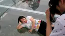 Seorang wanita berbaring saat difoto rekannya di atas platform kaca di Jurang Shilin, Beijing, Cina, (27/5). Platform ini luasnya mencapai 415 meter persegi. (REUTERS/Kim Kyung-Hoon)