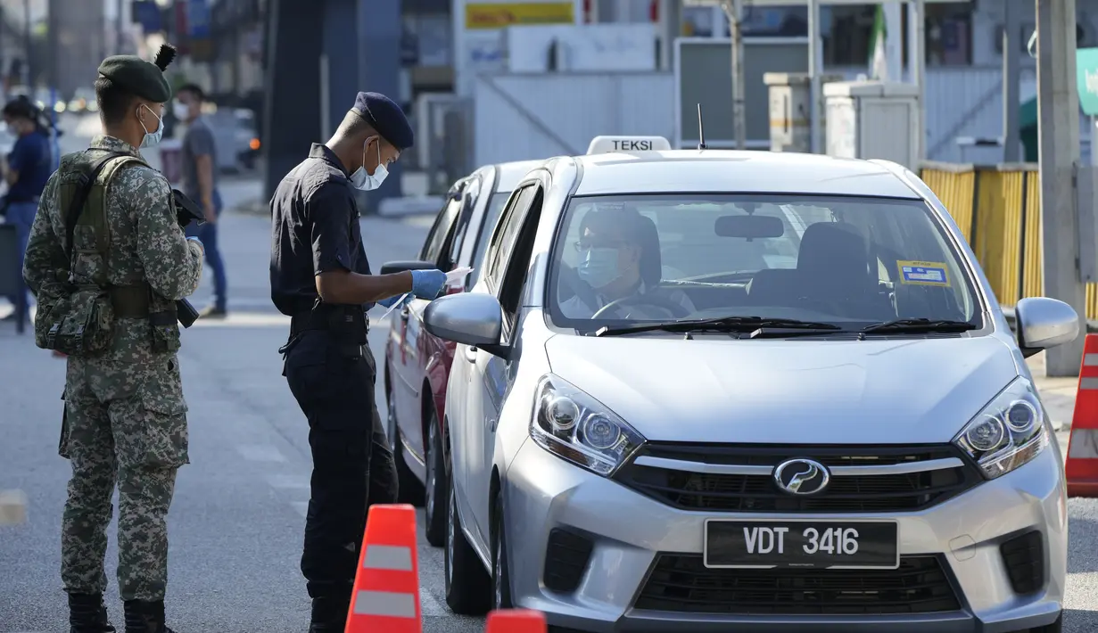 Polisi memeriksa penumpang di kendaraan pada hari pertama Perintah Kontrol Gerakan Penuh (MCO) di Kuala Lumpur, Malaysia (1/6/2021). Penguncian kedua dilakukan untuk mengatasi pandemi yang memburuk yang telah menempatkan sistem perawatan kesehatannya di ambang kehancuran. (AP Photo/Vincent Thian)