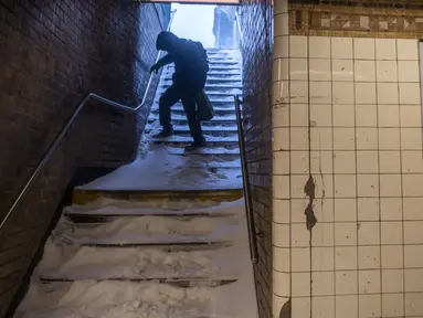 Seorang pria dengan hati-hati menuruni tangga subway yang tertutup salju selama badai salju di Bushwick, wilayah Brooklyn di New York, Sabtu (29/1/2022). Orang-orang dari New York City hingga Maine terbangun karena salju tebal dan angin kencang saat badai salju yang kuat melanda (AP/Britania Newman)