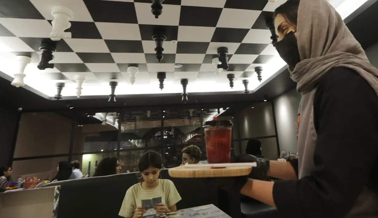Pelayan membawa minuman ringan di area permainan papan di kopi Geek di Jeddah, Arab Saudi, Kamis (11/11/2021).  Ruangan kafe mencakup ruang baca manga, bagian permainan papan, dan toko figur. (AP Photo/Amr Nabil)
