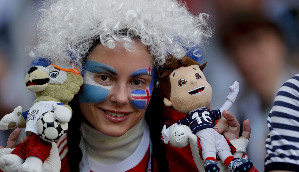 Suporter cantik dengan wajah bendera Argentina dan Islandia memegang maskot Piala Dunia 2018 di Spartak Stadium, Moskow, (16/6/ 2018). Argentina dan Islandia bermain imbang 1-1. (AP/Ricardo Mazalan)