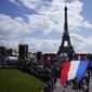 Seorang pria mengibarkan bendera Prancis di zona penggemar Olimpiade di Trocadero Gardens di depan Menara Eiffel di Paris, Minggu (8/8/2021). Pelepasan tongkat tuan rumah akan dibagi antara Stadion Olimpiade di Tokyo dan pesta publik dan konser di Paris. (AP Photo/Francois Mori)