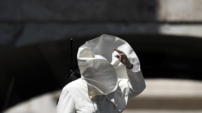 Embusan angin menyebabkan wajah Paus Fransiskus tertutup jubahnya sendiri saat memberkati umat setelah misa pada pertemuan dengan para pemuda di Lapangan Santo Petrus, Vatikan, Minggu (12/8). (AFP PHOTO / FILIPPO MONTEFORTE)