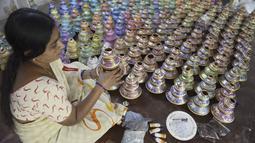 Perajin menunjukkan pot minyak tembikar atau diyas yang disimpan untuk dikeringkan menjelang Diwali, festival lampu Hindu, di luar bengkel di Hyderabad (4/11/2020). Diwali dirayakan selama lima hari berturut-turut.  (AFP Photo/Noah Seelam)