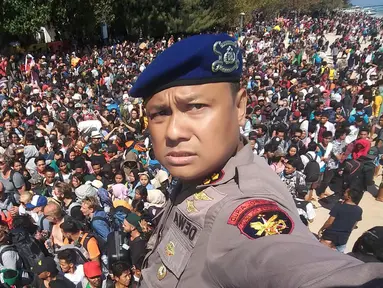 Kepala Polair Lombok, Dewa Wijaya berswafoto dengan latar ratusan orang yang berusaha meninggalkan Gili Trawangan, NTB, Senin (6/8). Lebih dari seribu turis dievakuasi dari pulau-pulau kecil di Gili Trawangan. (Handout/Indonesia Water Police/AFP)