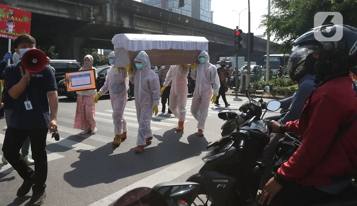 Petugas gabungan dari Kecamatan Cilandak dan Polsek Cilandak mengarak instalasi peti mati jenazah Covid-19 di kantor kecamatan Cilandak, Jakarta, Jumat (28/8/2020). Sosialisasi tersebut dilakukan untuk memberikan peringatan akan bahaya penularan virus Covid-19. (Liputan6.com/Herman Zakharia)