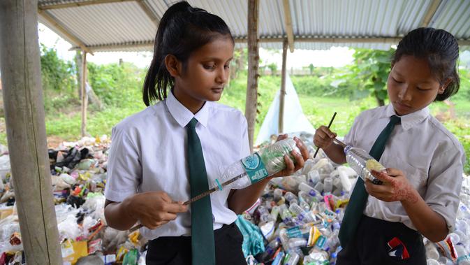 Siswa India memasukkan kantong plastik ke dalam botol untuk membuat 