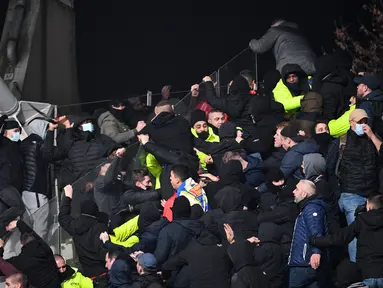 Petugas keamanan turun tangan di tribun penonton ketika para pendukung bentrok pada pertandingan 64 besar Piala Prancis antara Paris FC dan Olympique Lyon di stadion Charlety, Paris,  Jumat (17/12/2021). Laga pun dibatalkan menyusul kerusuhan penonton tersebut. (Bertrand GUAY/AFP)