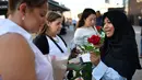 Seorang muslim membagikan bunga mawar disertai sebuah pesan kepada pejalan kaki di London Bridge, Minggu (11/6). Ribuan bunga mawar yang dibagikan sebagai solidaritas atas teror London itu merupakan hasil donasi para warga Muslim. (Ben STANSALL/AFP)
