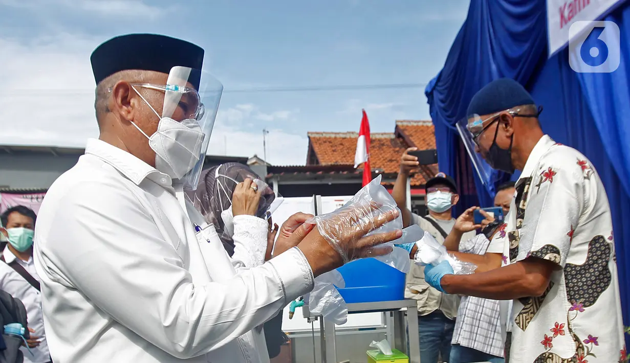 Calon Wali Kota Depok nomor urut 2 Mohammad Idris mengenakan sarung tangan plastik saat akan menggunakan hak pilihnya di TPS 14 Jatimulya, Depok, Rabu (9/12/2020). Pilkada Depok 2020 diikuti oleh Pradi Supratna-Afifah Alia serta Mohammad Idris dan Imam Budi Hartono. (Liputan6.com/Herman Zakharia)