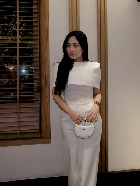 Kali ini, top putih dengan aksen wrapped juga menjadikan tampilan terlihat klasik.  [Foto: instagram/ Rachel Vennya]