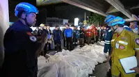 Perdana Menteri Thailand Anutin Charnvirakul, mengenakan pakaian biru, memeriksa lokasi kebakaran sementara jenazah para korban diletakkan berjejer di Bangkok, Thailand, Senin, 13 Juli 2026. (AP Photo/Sakchai Lalit)