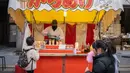 Seorang anak membeli ayam goreng pada kios makanan selama pekan raya akhir tahun di Distrik Nihonbashi, Tokyo, Jepang, 26 Desember 2022. Tak hanya menyuguhkan pemandangan indah dan makanan yang lezat, Jepang juga menjadi negara yang tepat untuk merayakan tahun baru. (Yuichi YAMAZAKI/AFP)