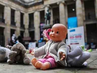 Boneka mainan diletakkan di halaman gedung Kongres Kolombia untuk memprotes kekerasan seksual terhadap anak-anak di Bogota, Selasa (20/11). Protes bertujuan untuk meningkatkan kesadaran tentang tanggung jawab perlindungan anak-anak. (DANIEL MUNOZ/AFP)