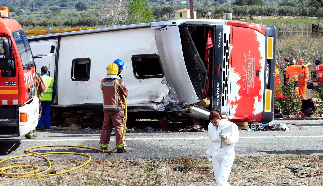 Petugas darurat dikerahkan ke lokasi kecelakaan sebuah bus berisi mahasiswa asing di Jalan Raya AP7 dekat Kota Freginals, Spanyol, Minggu (20/3). Sedikitnya 13 penumpang tewas dalam insiden itu sementara puluhan lainnya luka-luka. (PAU Barrena/AFP)