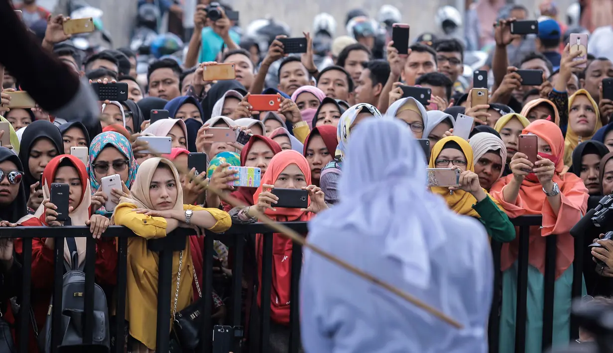 Antusiasme warga saat menyaksikan hukum cambuk terhadap pekerja seks komersial (PSK) online di halaman Masjid Jamik Lueng Bata, Banda Aceh, Aceh, Jumat (20/4). Dua PSK online masing-masing mendapat hukuman 11 kali cambukan. (AP Photo/Heri Juanda)