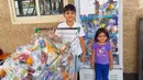 Dua orang anak berfoto di depan kulkas dan trolli yang berisi makanan dan minuman jelang bulan Ramadan di Dubai. Makanan dan minuman untuk berbuka puasa ini disediakan gratis untuk pekerja dan buruh. (www.instagram.com/ramadanfridgesdxb)
