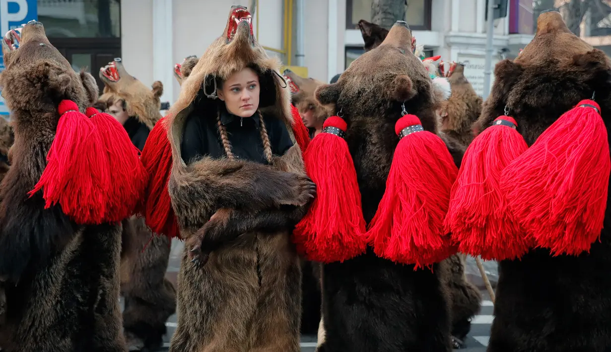 Seorang gadis mengenakan kostum beruang bersiap mengikuti ritual tahunan di Piatra Neamt, Rumania Utara (28/12). Tradisi yang berasal dari masa pra-Kristen ini bertujuan untuk menangkal kejahatan. (AP Photo/Vadim Ghirda)