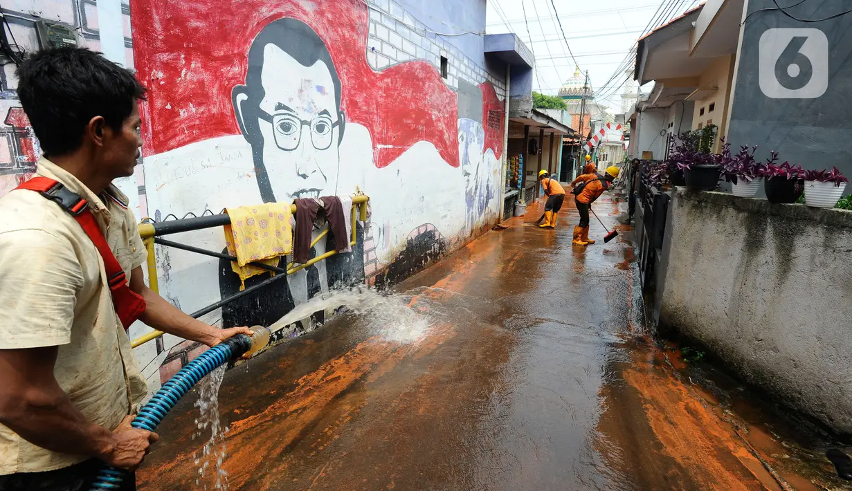 Petugas membersihkan tanah merah berlumpur   di Jalan PLN Raya Gandul  di Kecamatan Cinere, Depok, Jawa Barat, Rabu (31/8/2022). Tanah merah naik dari dalam tanah akibat  proyek pekerjaan Kabel SKTT 150kV Gandul-Kemang,  menyebabkan jalan dipenuhi tanah merah berlumpur. (merdeka.com/Arie Basuki)