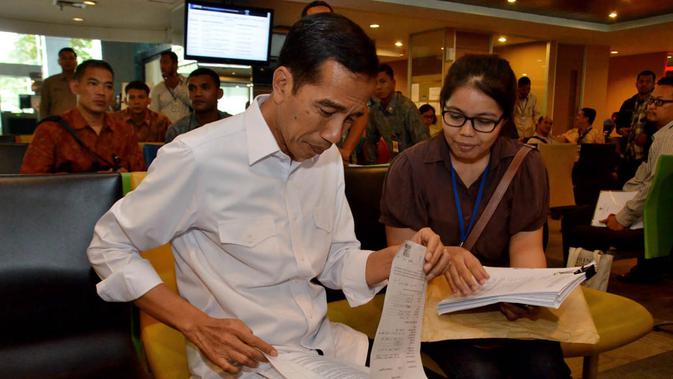 Presiden Jokowi bertanya sambil memeriksa berkas milik masyarakat yang sedang mengurus perizinan, terutama yang terkait penanaman modal asing, Jakarta, Selasa (28/10/14). (Rumgapres/Agus Suparto)