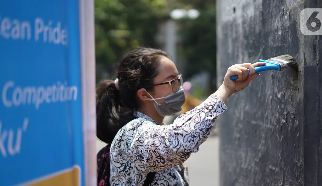 Pelajar membersihkan coretan yang mengotori tembok saat kericuhan dalam unjuk rasa di Senayan, Jakarta, Jumat (4/10/2019). Para siswa dan alumni SMA menutup coret-coretan  itu sekaligus mengampanyekan cinta damai dalam praktik demokrasi di Indonesia. (Liputan6.com/Immanuel Antonius)