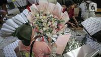Perajin menata buket atau karangan bunga di Pasar Bunga Rawa Belong, Jakarta, Senin (14/2/2022). Perajin buket setempat mengaku permintaan pesanan karangan bunga yang biasa dihadiahkan saat hari kasih sayang atau Valentine Day tersebut menurun. (Liputan6.com/Faizal Fanani)