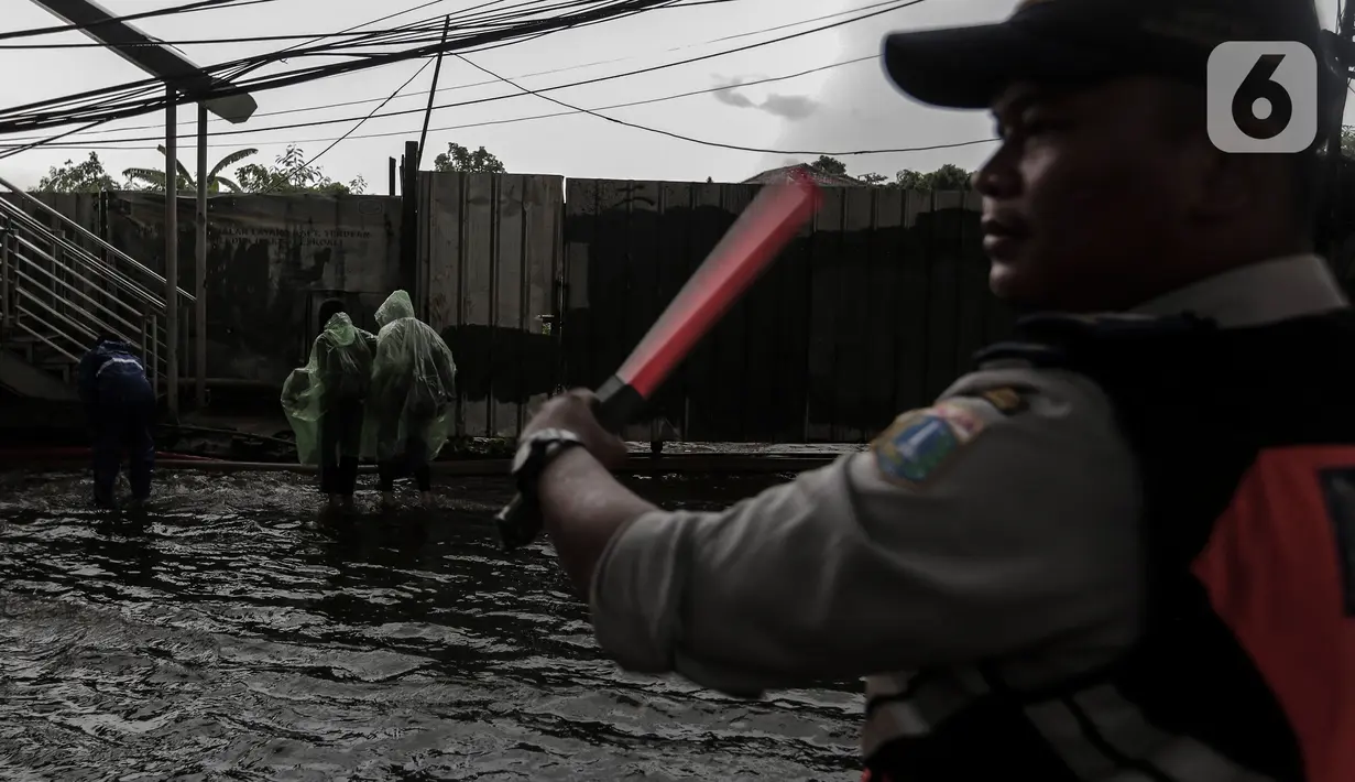 Petugas mengatur lalu lintas saat banjir menggenangi kawasan Seskoal - Cipulir, Jakarta, Selasa (4/4/2022). Hujan yang mengguyur wilayah Ibu Kota Jakarta mengakibatkan banjir menggenangi kawasan Simpang Seskoal, Kebayoran Lama, Jakarta. Banjir setinggi 50cm - 1 meter disebabkan saluran pembuangan berukuran kecil tersumbat. (Liputan6.com/Johan Tallo)