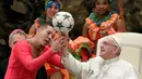 Paus Fransiskus diajari cara memutar bola di jari oleh anggota kelompok sirkus Kuba ketika mereka tampil dalam audiensi umum mingguan di Vatikan, Rabu (2/1). (AP Photo/Andrew Medichini)
