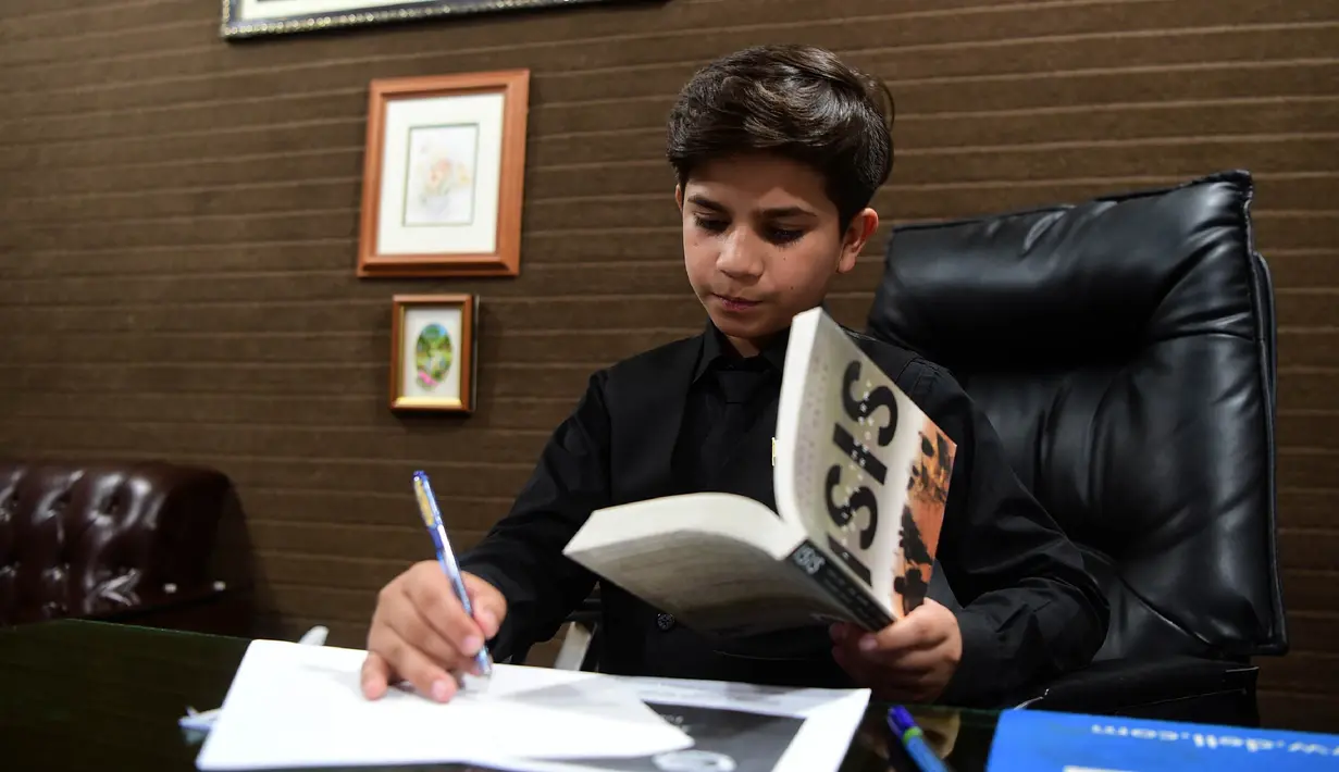 Motivator cilik Hammad Safi membuat catatan di sebuah akademi bahasa di Peshawar, Pakistan (3/4). Saat memberi motivasi di depan umum, Hammad Safi selalu percaya diri dengan dandanan rapih dan elegan. (AFP/Abdul Majeed)