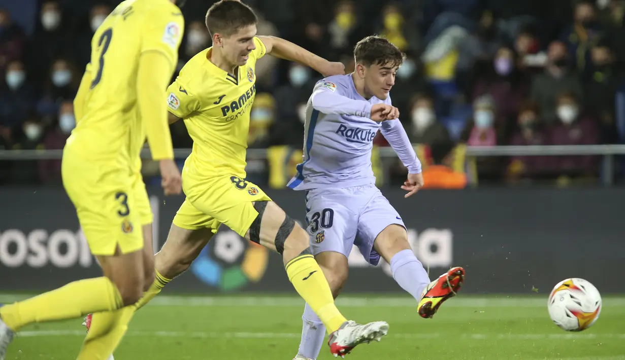 Gelandang Barcelona Gavi melakukan tendangan dibayangi pemain Villarreal pada lanjutan La Liga di Estadio de la Ceramica, Minggu (28/11/2021) dini hari WIB. Barcelona menang dengan menghajar tuan rumah Villlarreal 3-1. (AP Photo/Alberto Saiz)