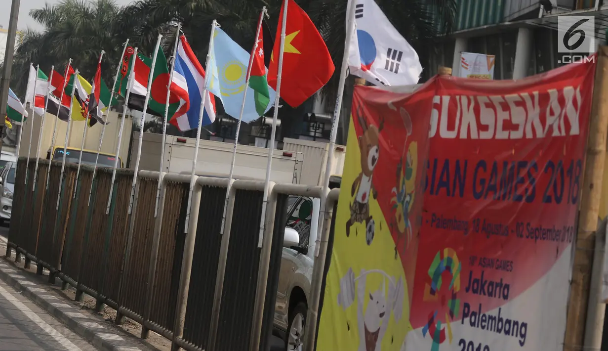 Deretan bendera negara-negara kontestan Asian Games 2018 yang terpasang menggunakan bambu di pagar pembatas Jalan Pluit Selatan Raya, Jakarta, Kamis (19/7). Bendera-bendera itu diikat di sebatang bambu yang dicat putih. (Liputan6.com/Arya Manggala)