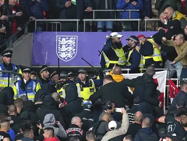 Suporter Hungaria bentrok dengan polisi saat dimulainya laga Kualifikasi Piala Dunia 2022 melawan Inggris di Stadion Wembley, Rabu (13/10/2021) dini hari WIB. Bentrokan terjadi saat polisi berusaha menangkap penonton yang melakukan pelecehan rasial terhadap petugas stadion. (Nick Potts/PA via AP)
