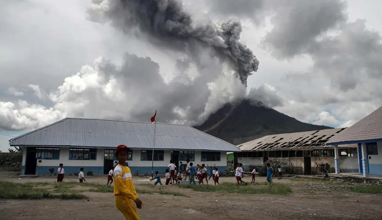 Sejumlah murid SD bermain di sekolah mereka saat erupsi Gunung Sinabung di Karo, Sumatera Barat (13/11). Meski erupsi, aktivitas kegiatan belajar di sekolah di Kabupaten Karo tersebut berjalan seperti biasa. (AFP Photo/Ivan Damanik)