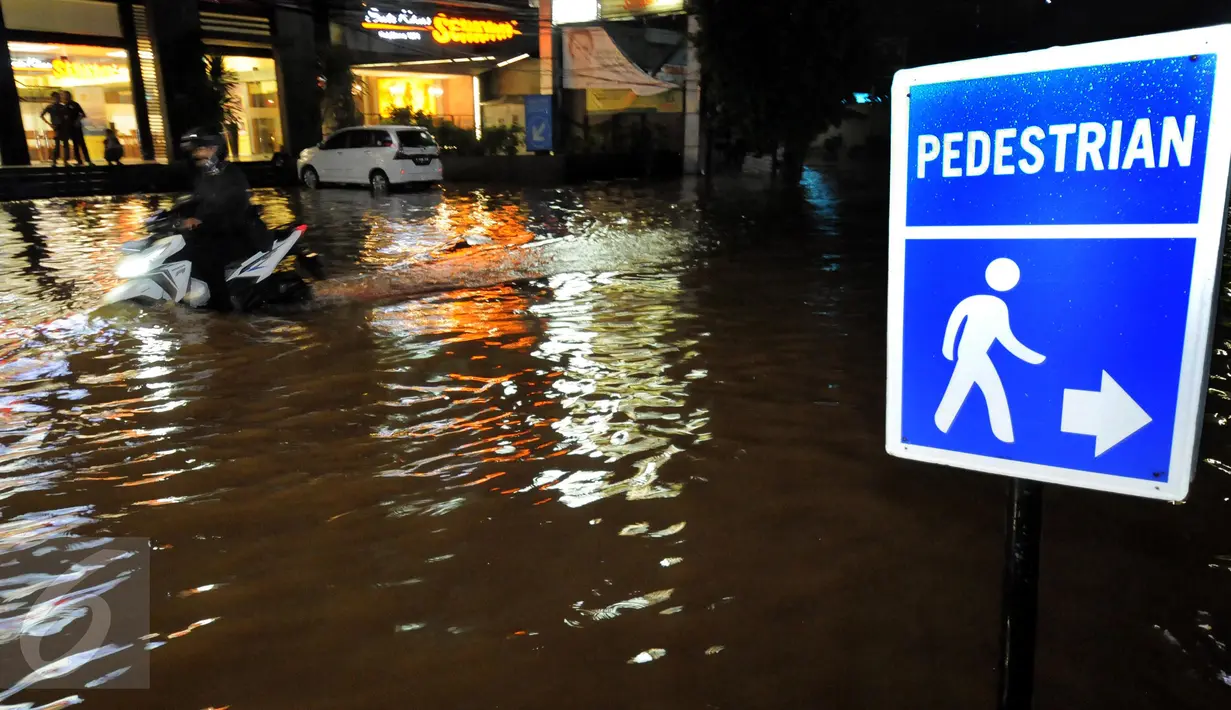 Seorang pengendara motor menerobos banjir yang menggenangi kawasan Kemang, Jakarta, Minggu (25/9). Hujan deras yang mengguyur sebagian besar kawasan di Jakarta, Minggu malam, membuat wilayah Kemang terendam banjir lagi. (Liputan6.com/Helmi Afandi)