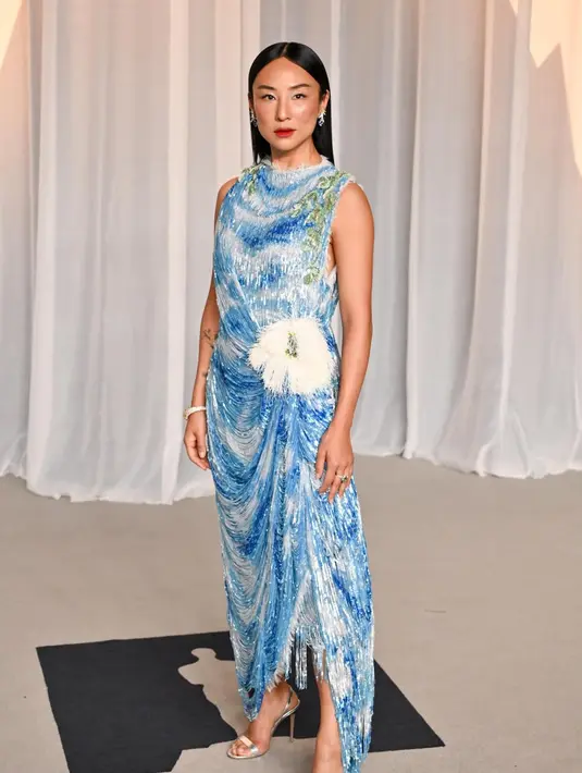 Greta Lee mengenakan gaun Dior Haute Couture koleksi Musim Gugur-Musim Dingin 2026-2027 yang terbuat dari sifon sutra putih. Gaun ini dihiasi sulaman motif pemandangan langit yang terdiri dari payet, dilapisi dengan aksen rumbai-rumbai berpayet yang menjuntai, serta dipercantik dengan hiasan bunga eukaliptus berukuran besar pada bagian pinggul. Tepian gaun dibiarkan berdesain serabut atau frayed edges. / Foto dok: Dior.