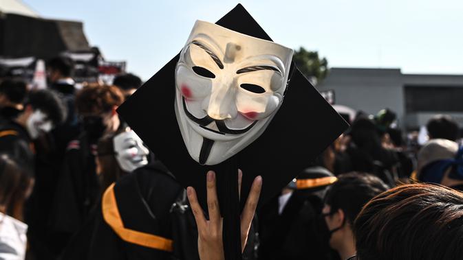 Mahasiswa mengenakan topeng Guy Fawkes selama aksi protes pada upacara kelulusan mereka di Chinese University of Hong Kong, Hong Kong, Kamis (7/11/2019). Sekitar seribu mahasiswa mengabaikan larangan mengenakan topeng yang dikeluarkan pemerintah pada Oktober 2019. (Philip FONG / AFP)
