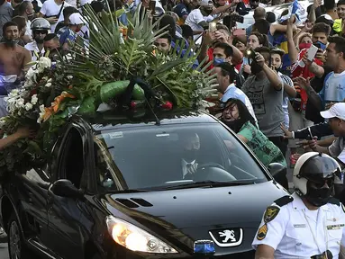 Penggemar berkerumun di samping mobil jenazah legenda sepak bola Argentina, Diego Armando Maradona, dalam perjalanan dari istana kepresidenan Casa Rosada ke pemakaman, Kamis (26/11/2020) waktu setempat. Diego Maradona meninggal karena serangan jantung pada usia 60 tahun. (AFP/Raul Fferrari/ TELAM)