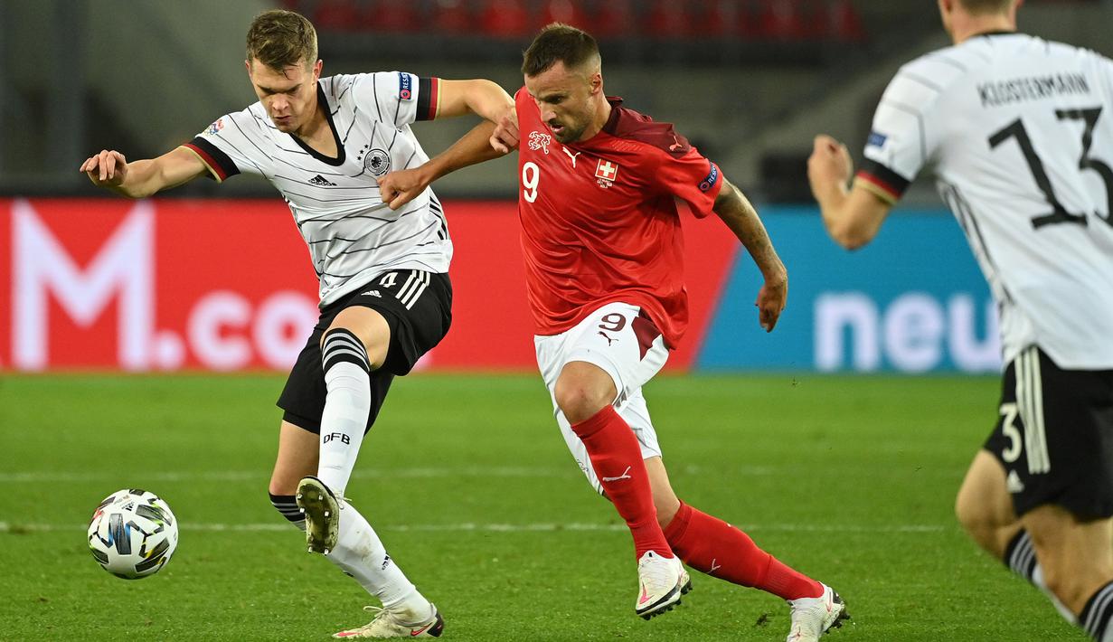Bek Jerman, Matthias Ginter, berebut bola dengan penyerang Swiss, Haris Seferovic, pada laga lanjutan UEFA Nations League 2020/2021 di RheinEnergie Stadion, Rabu (14/10/2020). Jerman bermain imbang 3-3 atas Swiss. (AFP/Ina Fassbender)