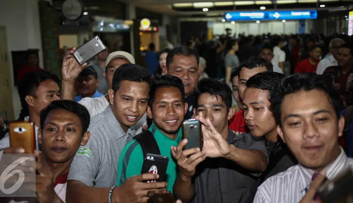 Gelandang serang tim nasional Sepak Bola Indonesia, Andik Vermansyah berfoto bersama masyarakat saat tiba di Bandara Soekarno Hatta, Jakarta, Kamis (8/12). (Liputan6.com/Faizal Fanani)