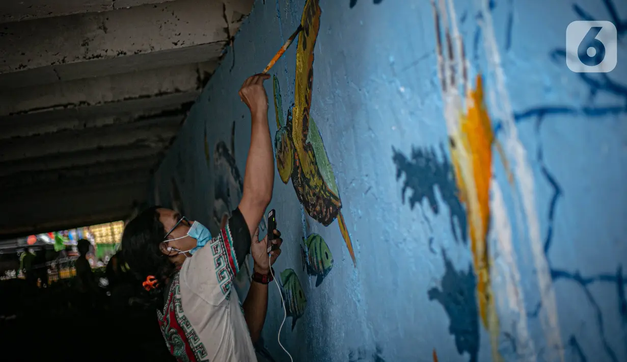 Mahasiswa Institut Kesenian Jakarta (IKJ) menyelesaikan pembuatan mural di kolong Jembatan Pegangsaan, Menteng, Jakarta, Selasa (26/1/2021). Pembuatan mural tersebut bertujuan mempercantik kawasan bantaran kali dan sebagai ruang interaksi warga. (Liputan6.com/Faizal Fanani)