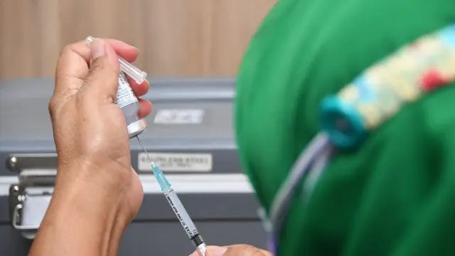 Dokter memasukkan vaksin Moderna melalui jarum suntik