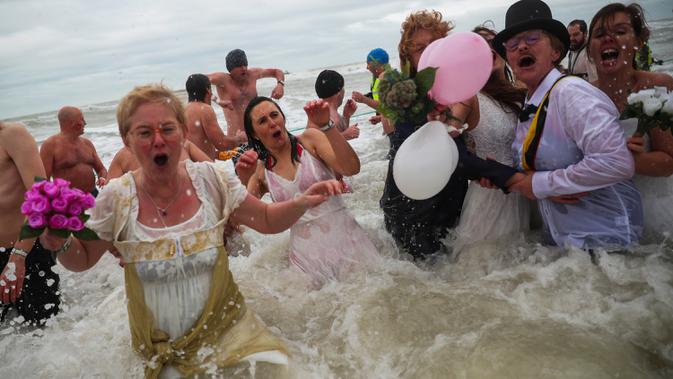 Orang-orang dengan kostum warna-warni menyerbu perairan Laut Utara  untuk merayakan akhir pekan pertama Januari 2020 di Ostend, Belgia, Sabtu (4/1/2020). Cuaca dingin tak menghalangi mereka untuk menceburkan diri ke laut yang merupakan salah satu tradisi tahun baru. (AP/Francisco Seco)
