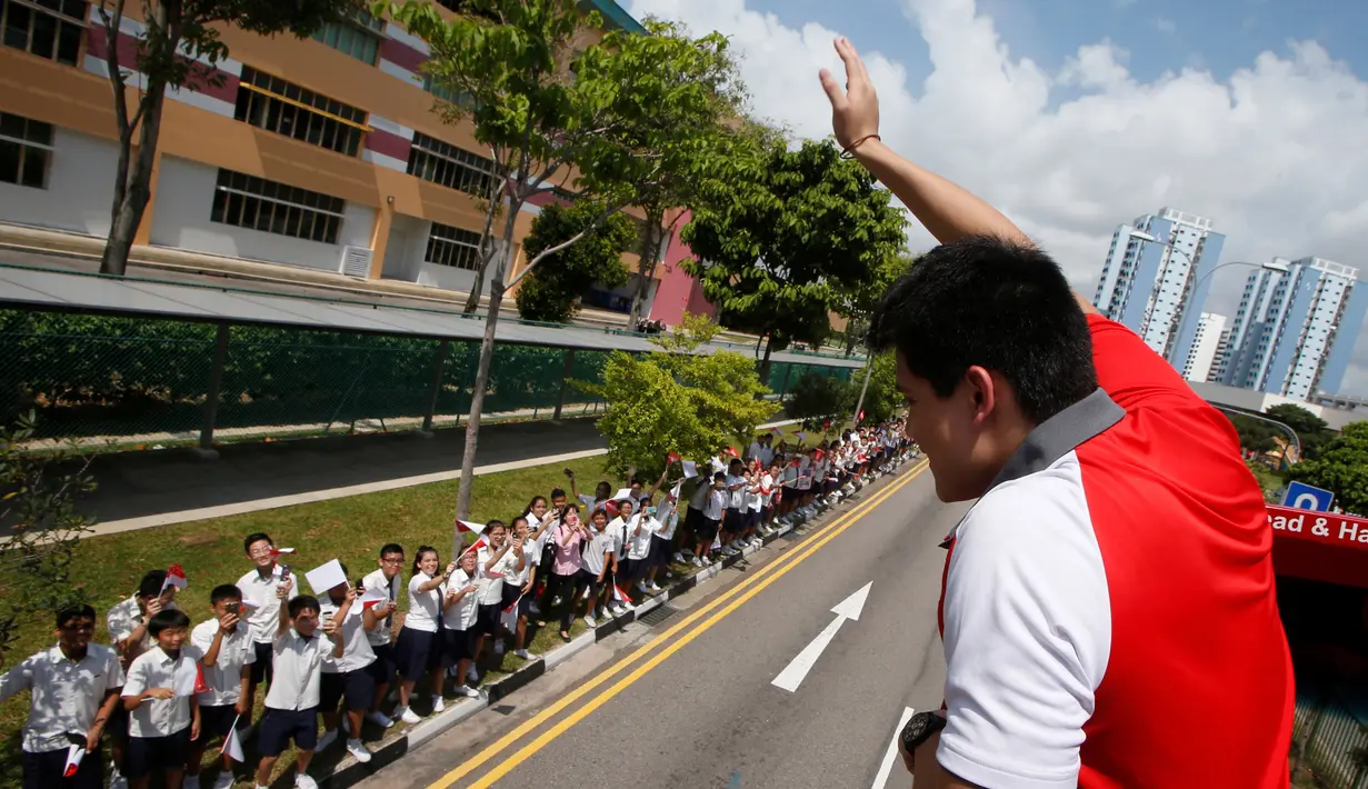 Atlet renang, peraih medali emas pertama Singapura, Joseph Schooling menyapa siswa sekolah saat keliling  menggunakan bus terbuka pada parade kemenangan di Singapura (18/08). (REUTERS/Edgar Su)