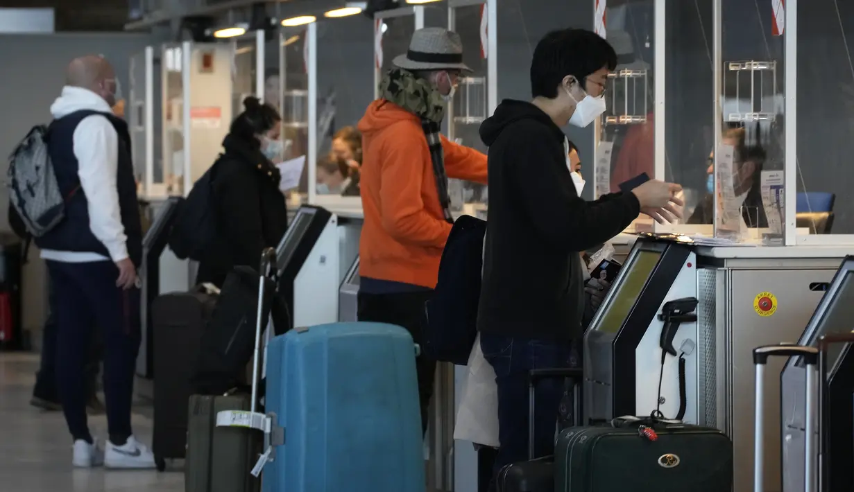 Pelancong untuk Amerika Serikat menunjukkan dokumen mereka di meja check-in di bandara Charles de Gaulle, utara Paris, Senin (8/11/2021). Pencabutan pembatasan perjalanan memungkinkan wisatawan untuk melakukan perjalanan yang lama tertunda. (AP Photo/Christophe Ena)
