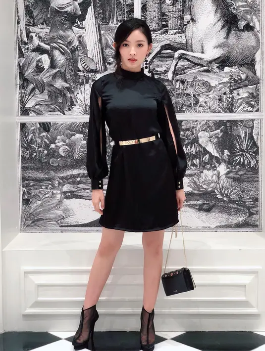 Sementara untuk tampil anggun, Natasha mengenakan dress pendek hitam dengan detail puff sleeve. Aksen gold belt dan transparent boots memperkuat kesan bold pada penampilannya.